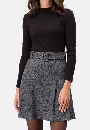 Zwarte top met lange mouwen gecombineerd met een grijze hondentandrok met een aangesloten taille en een gespceintuur, voorzien van een geplooid ontwerp.