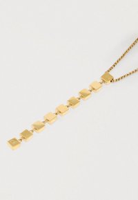 Χρυσό κολιέ με μια σειρά από συνδεδεμένα τετράγωνα κρεμαστά κοσμήματα με γυαλιστερές και υφασμάτινες επιφάνειες, κρεμασμένο σε μια λεπτή αλυσίδα.