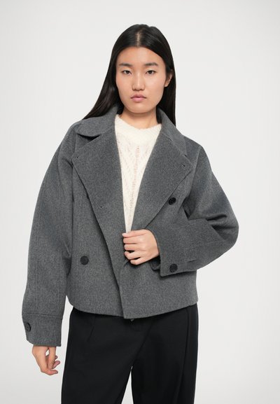 Giacca cropped in misto lana grigia con ampio colletto e chiusura doppiopetto. Presenta bottoni grandi e spalle cadenti per un fit rilassato.