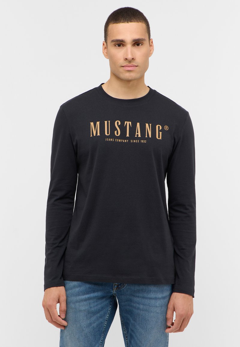 Zwarte longsleeve t-shirt van katoen, met een gedurfde gouden "MUSTANG" logo over de borst en een klassieke ronde hals.