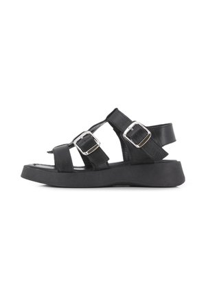 Sandalias de cuero negro con suela plana, diseño de múltiples correas con hebillas plateadas ajustables y una superficie texturizada.