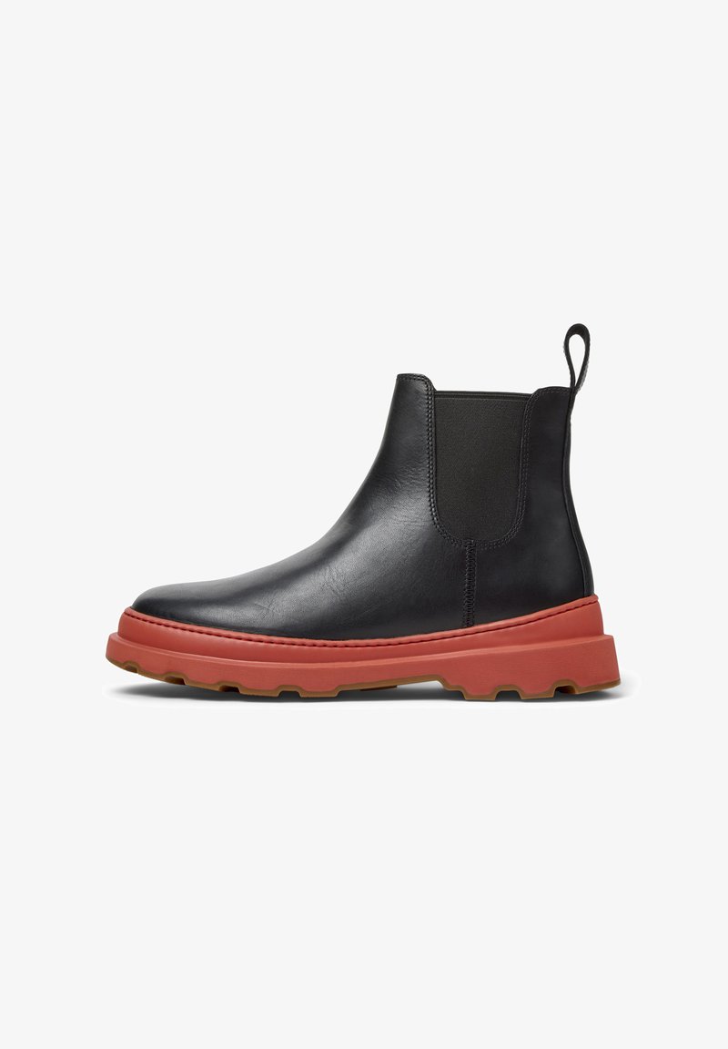 Stivale Chelsea in pelle nera con suola in gomma rosso-arancio, dotato di pannelli elastici laterali e di un cinturino per il sollevamento, presentato su uno sfondo bianco.