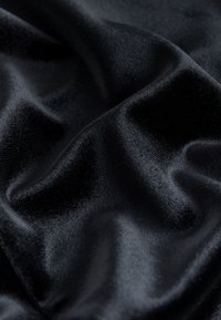 Tessuto di raso nero con una texture liscia e lucida, che mostra pieghe morbide e una leggera lucentezza. Nessun motivo o accento visibile.