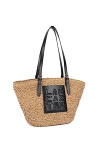 Sac fourre-tout tressé de couleur tan avec des doubles anses en cuir noir et une pièce en cuir noir embossée du mot "LANCASTER" sur le devant.