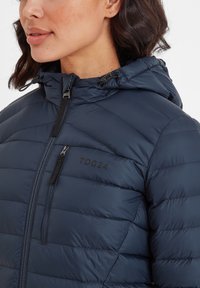 Navy puffer jacket featuring a zippered front, adjustable hood, and stitched panels. Black "TOG24" logo on the chest. Smooth texture.