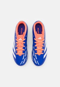 Crampons de football bleus avec des rayures blanches et des lacets orange. Matière synthétique lisse avec des accents texturés et un col rembourré.