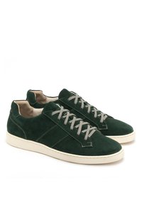 Zielone zamszowe trampki z szarymi sznurówkami, białymi gumowymi podeszwami i niską cholewką. Charakteryzują się przeszywanymi akcentami i miękką, teksturowaną powierzchnią.