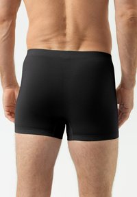 Boxer briefs en tissu extensible noir avec une finition texturée, présentant une coupe ajustée et une ceinture élastique, affichant un design lisse.