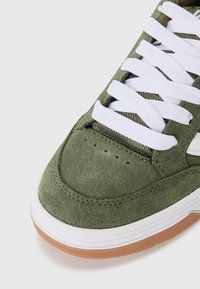 Zapatillas de ante verde con cordones blancos, acentos de malla, detalles perforados y suela de goma. Punta redondeada y cuello acolchado.