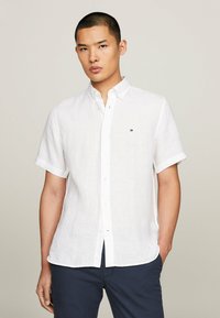 Camicetta bianca in lino a maniche corte con colletto button-down, caratterizzata da un piccolo logo. Tessuto strutturato, vestibilità casual e orlo dritto.