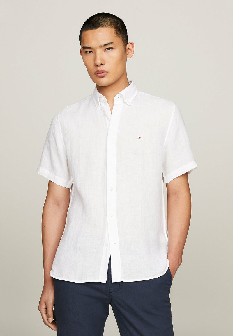 Camicetta bianca in lino a maniche corte con colletto button-down, caratterizzata da un piccolo logo. Tessuto strutturato, vestibilità casual e orlo dritto.