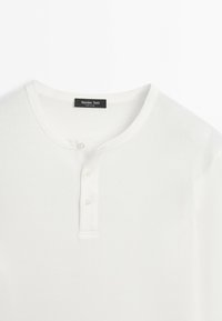 White long-sleeve Henley shirt with round neckline and three buttons on the placket, labeled Massimo Dutti.