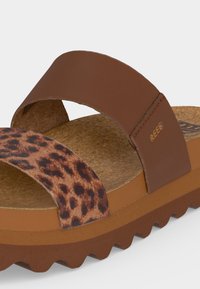 Καφέ σανδάλι με δύο λουριά, ένα μονόχρωμο καφέ και ένα με λεοπάρ μοτίβο, φελλό πάτο και καφέ ραβδωτή σόλα.