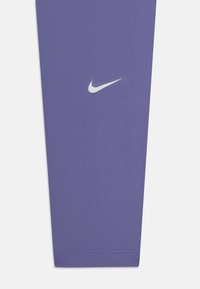 Leggings de sport violets en tissu lisse et extensible. Présentent un petit logo Nike blanc près de la cheville et des coutures soignées à l'ourlet.
