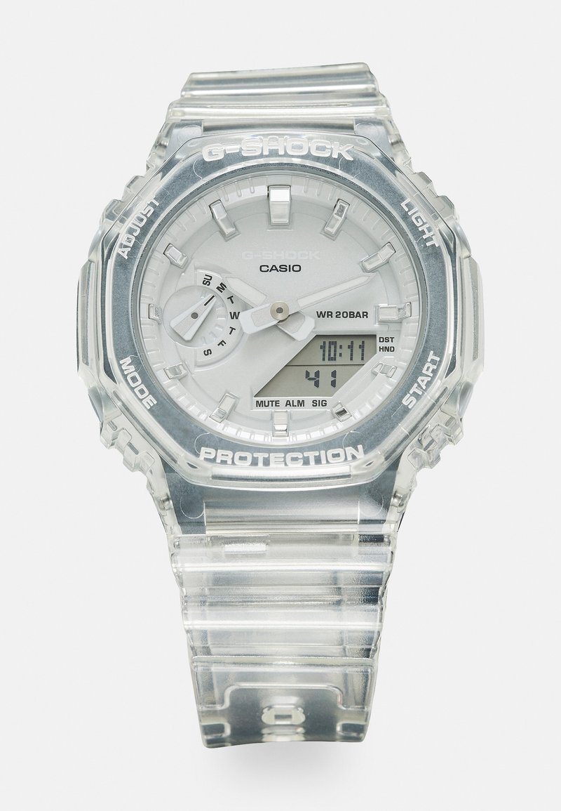 Montre Casio G-Shock avec un boîtier et un bracelet en résine transparentes. Présente un cadran blanc, trois sous-cadrans et un affichage numérique avec des étiquettes. Étanche jusqu'à 20 bars.