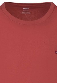 T-shirt di cotone rosso con collo a giro e maniche corte, con un piccolo contrassegno logo Levi's sul lato inferiore destro. Texture liscia.