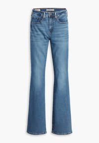 Jeans de corte acampanado en denim de lavado medio, con cinco bolsillos, pasadores para cinturón y un sutil efecto de desvanecimiento en los muslos y las rodillas.