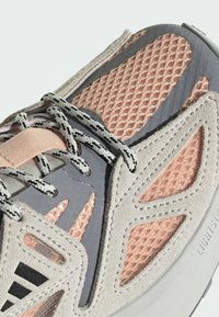 Lättviktig sneaker med ett överdel i grå mocka och mesh, med rosalila accenter och svarta detaljer, texturerade mönster och grå snören.