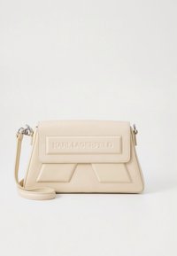 Beige läderhandväska med klaffstängning, präglad logotyp på framsidan, geometriska designdetaljer, justerbar rem, slät yta.