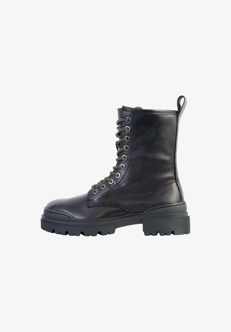 Botte de combat en cuir noir à lacets, semelle à gros crampons et languette à l'arrière, vue de côté sur fond blanc.