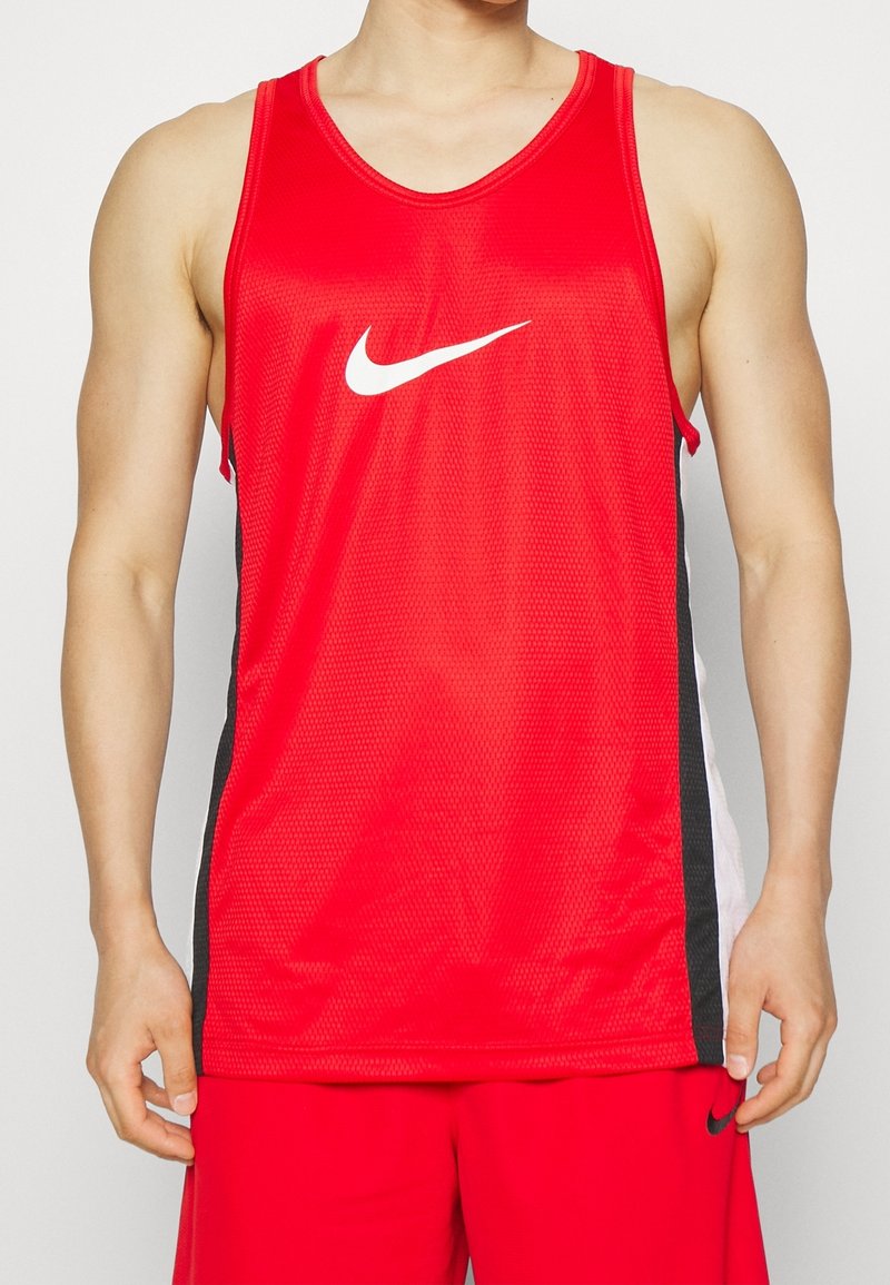 Homme portant un maillot de sport rouge sans manches avec un logo blanc Nike et un short rouge assorti avec des bandes latérales noires.