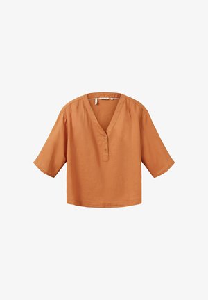 Blouse ample à manches courtes de couleur rouille avec encolure en V et deux boutons sur la patte de boutonnage avant, en tissu léger.
