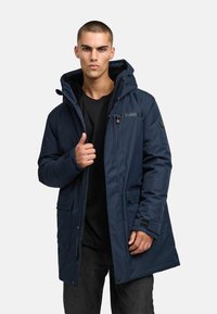 Tumši zils, pamatots jaka ar noņemamu kapuci, ar rāvējslēdzēju un pogu aizdari, četriem kabatām un gludu virsmas tekstūru, apvienota ar melnu kreklu.