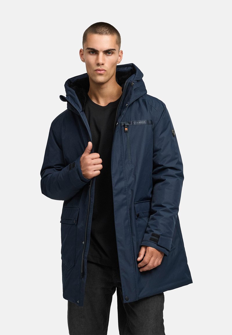 Tumši zils, pamatots jaka ar noņemamu kapuci, ar rāvējslēdzēju un pogu aizdari, četriem kabatām un gludu virsmas tekstūru, apvienota ar melnu kreklu.