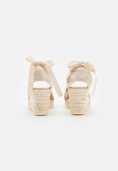 Wedges in beige espadrille con cinturini in tessuto intrecciato, legati con nastri di raso, e tacco in corda testurizzato con forma arrotondata e suola liscia.