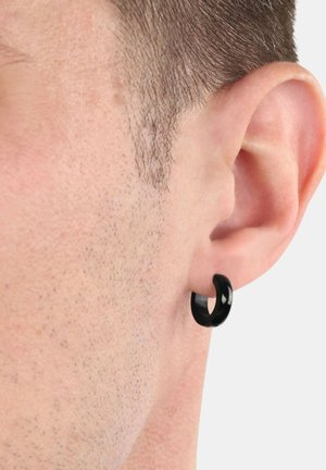 Boucle d'oreille noire en forme de hoop, finition lisse avec une texture brillante, portée dans le lobe de l'oreille, mettant en valeur un design circulaire et une forme sans couture.