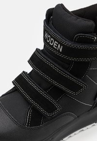 Schwarze High-Top-Sneaker aus einer Kombination von strukturiertem Mesh- und Wildledermaterialien. Verfügt über drei verstellbare Klettverschlüsse und weiße Nähte.