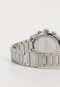 Silver stainless steel watch with a linked band, featuring a polished finish, round face, and engraved brand name on the clasp.