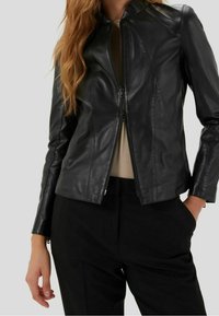 Veste en cuir noir avec un design ajusté, un col haut et une fermeture éclair à l'avant. Présente une texture lisse et des détails de couture subtils.