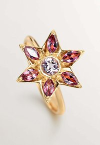 Anillo de oro con un engaste en forma de estrella que presenta una gema redonda y transparente en el centro y seis gemas marquise rosas como puntos de la estrella.