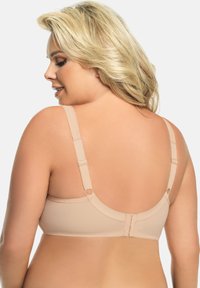 Beige bh met verstelbare bandjes, een soepele textuur en een haak-en-oogsluiting aan de achterkant. Voorzien van ronde hardwareaccenten.