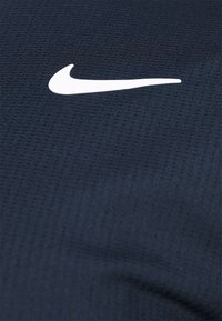 Námořnická sportovn�í tkanina s bílým logem Nike swoosh, texturovaný povrch s jemnými diagonálními pruhy, lehký a prodyšný design.