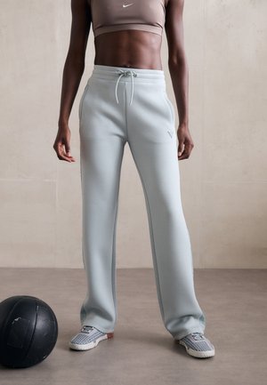 Lys blå, vide sweatpants med justerbart liv, med sidelommer og teksturert overflate. Atletiske joggesko i nærheten.