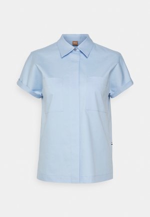 Helles blaues Kurzarmhemd mit klassischem Kragen, zwei Fronttaschen und Knopfverschluss. Aus weichem, glattem Stoff gefertigt.