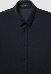 Camicia nera con bottoni, con una sottile texture a macchie, caratterizzata da un colletto classico e patta frontale con bottoni neri. Taglia L visibile.
