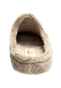 Beige pluche slof, zachte vacht buitenkant, ronde vorm, gevoerde binnenkant, platte zool, met label zichtbaar van binnen.