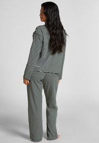 Gestreepte loungewear set in donkergroen en wit, met lange mouwen, losse broek, zachte stof en een relaxte pasvorm.