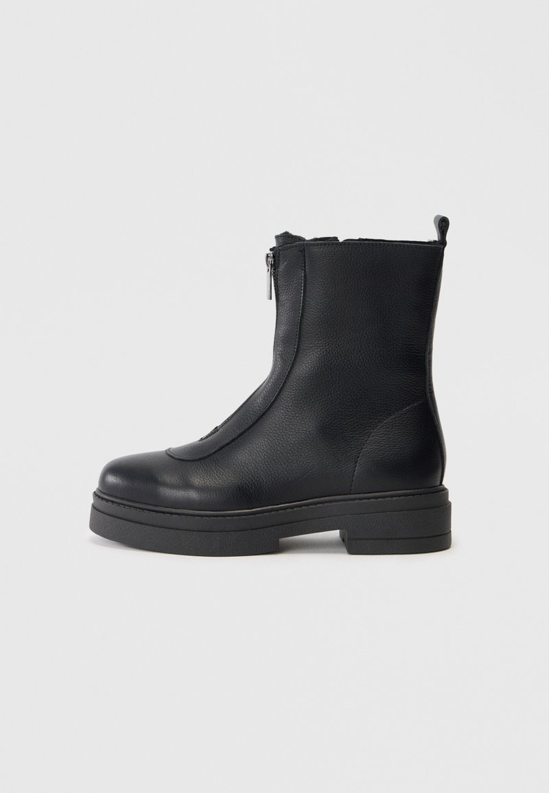 Bottines noires en cuir avec une fermeture éclair sur le côté, bout arrondi, surface texturée et semelle en caoutchouc épaisse. Design épuré et minimaliste.