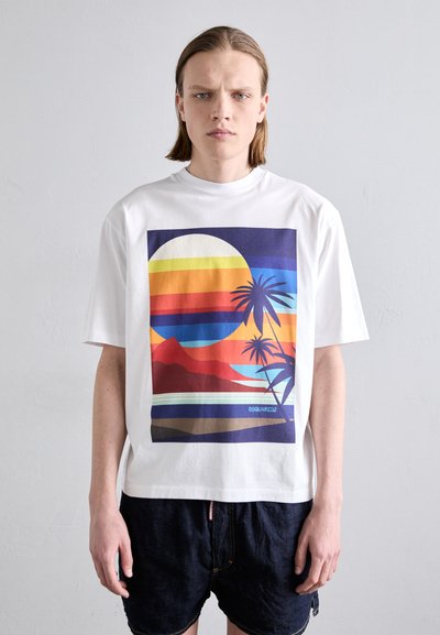 T-shirt blanc à manches courtes avec un graphisme vibrant représentant un coucher de soleil, des montagnes et des palmiers dans des nuances de rouge, bleu et jaune.