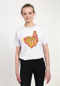 Camiseta de algodón blanca con un gráfico colorido de "Care Bears 40th" que presenta un diseño de oso y corazón. Mangas cortas, ajuste estándar.