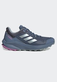 Zapatilla de trail running azul con parte superior de malla, detalles en plata, talón rosa y suela texturizada diseñada para ofrecer agarre en terrenos variados.
