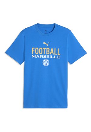 Blauw T-shirt met korte mouwen, geel Puma-logo, gele "FOOTBALL," witte "MARSEILLE," en een rond wit embleem onder de tekst.