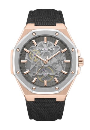 Orologio automatico Kenneth Cole con lunetta ottagonale in tonalità oro rosa, quadrante con ingranaggi visibili, indici dorati e cinturino in tessuto nero.