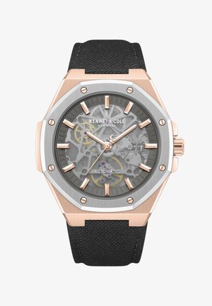 Montre automatique Kenneth Cole avec lunette octogonale couleur or rose, cadran à engrenages apparents, index dorés et bracelet en tissu noir.