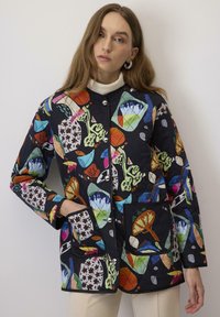 Giacca nera trapuntata con motivi astratti colorati, bottoni a pressione argentati e due tasche frontali con accenti in tessuto a contrasto.