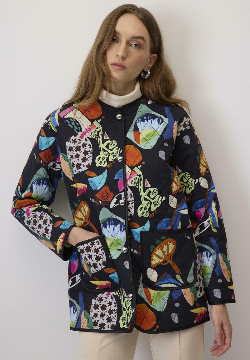 Giacca nera trapuntata con motivi astratti colorati, bottoni a pressione argentati e due tasche frontali con accenti in tessuto a contrasto.